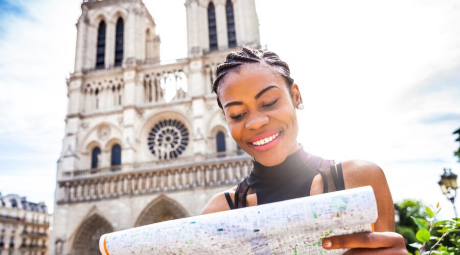 Young black women walking in Paris in the city center talking and texting on the phone and commuting using one of public city bikes.